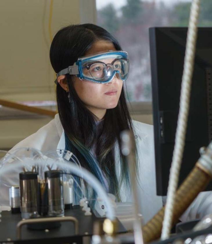 student in lab wearing goggles and viewing a monitor 